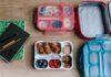 Школьное питание в Канаде: новая программа меняет привычный уклад Top view of composed plastic lunchboxes near copybooks under pencils on wooden table