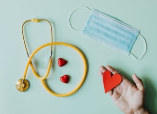 В Канаде создан новый национальный консультативный комитет по профилактике Top view of crop anonymous person hand with red paper heart on table with stethoscope and medical mask for coronavirus prevention