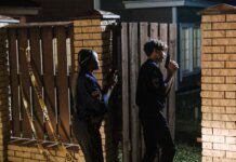 В Уитби арестован мужчина по обвинению в домогательстве к детям Two police officers investigate a crime scene at night, entering a house with caution.