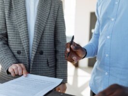 Two professionals reviewing business documents and discussing details in an office setting.