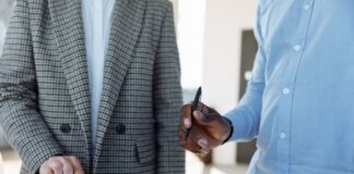 Two professionals reviewing business documents and discussing details in an office setting.