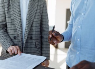 Канада станет со-лидером многонациональной дивизии НАТО на севере Латвии Two professionals reviewing business documents and discussing details in an office setting.