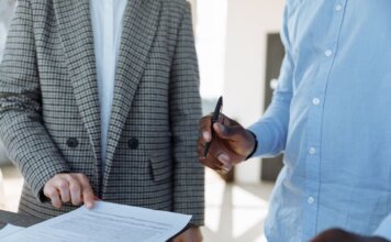 Канада станет со-лидером многонациональной дивизии НАТО на севере Латвии Two professionals reviewing business documents and discussing details in an office setting.