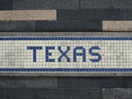 Unique mosaic tile artwork spelling 'Texas' on a sidewalk in Houston, TX.