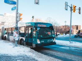Urban bus navigating snowy streets at a city intersection during daytime winter.