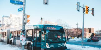 Urban bus navigating snowy streets at a city intersection during daytime winter.