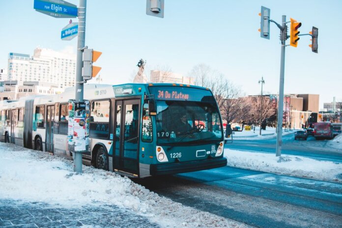 Urban bus navigating snowy streets at a city intersection during daytime winter. Urban bus navigating snowy streets at a city intersection during daytime winter.
