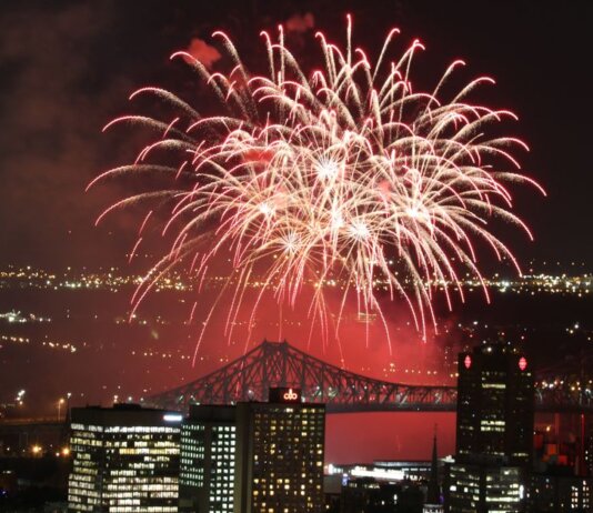 Vibrant fireworks exploding over city skyline at night, showcasing a festive celebration.