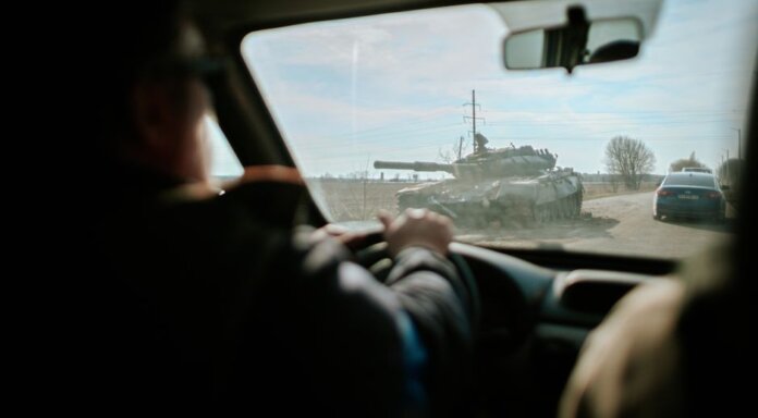 View from inside a car driving past a military tank on a road in Ukraine. View from inside a car driving past a military tank on a road in Ukraine.
