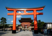 View of the iconic Torii gate leading to Fushimi Inari Shrine in Kyoto, Japan, a popular tourist attraction.
