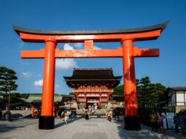 View of the iconic Torii gate leading to Fushimi Inari Shrine in Kyoto, Japan, a popular tourist attraction.