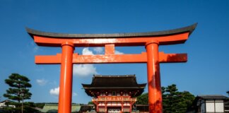 View of the iconic Torii gate leading to Fushimi Inari Shrine in Kyoto, Japan, a popular tourist attraction.
