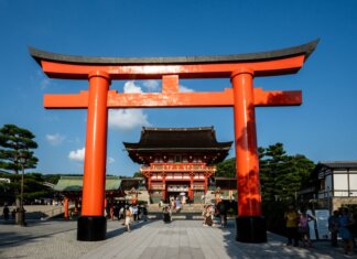 View of the iconic Torii gate leading to Fushimi Inari Shrine in Kyoto, Japan, a popular tourist attraction.