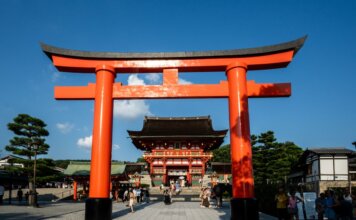 View of the iconic Torii gate leading to Fushimi Inari Shrine in Kyoto, Japan, a popular tourist attraction.
