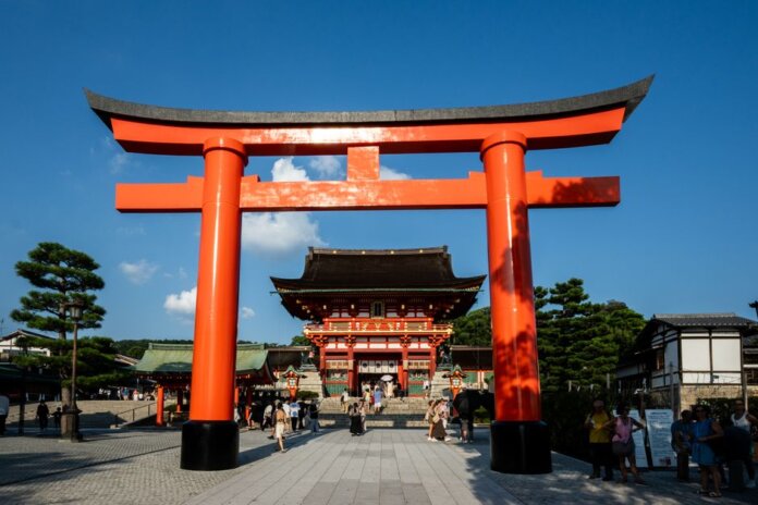 View of the iconic Torii gate leading to Fushimi Inari Shrine in Kyoto, Japan, a popular tourist attraction.
