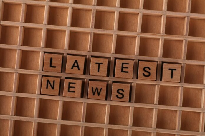 Wooden letter blocks spelling Latest News on a grid background, ideal for media themes.