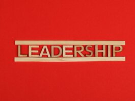 Wooden letters spelling leadership on a vibrant red background, conveying bold concepts.