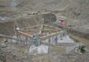 Workers constructing a building foundation with rebar and wooden supports outdoors.
