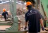 Канада и Манитоба помогут пострадавшим от тарифов работникам Workers wearing protective gear operating machinery in a factory environment, focusing on safety and production.