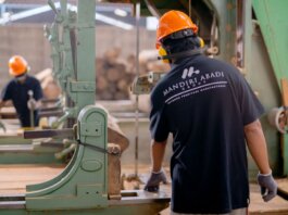 Workers wearing protective gear operating machinery in a factory environment, focusing on safety and production.