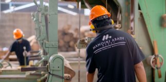 Workers wearing protective gear operating machinery in a factory environment, focusing on safety and production.
