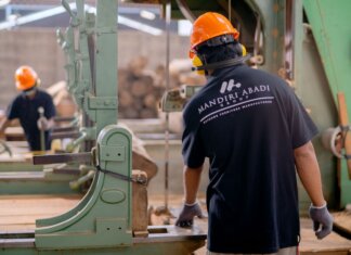 Канада и Манитоба помогут пострадавшим от тарифов работникам Workers wearing protective gear operating machinery in a factory environment, focusing on safety and production.