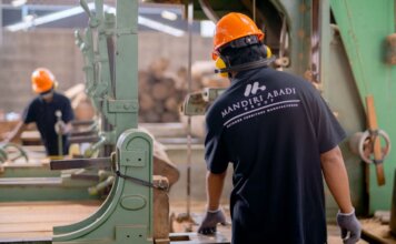 Workers wearing protective gear operating machinery in a factory environment, focusing on safety and production.