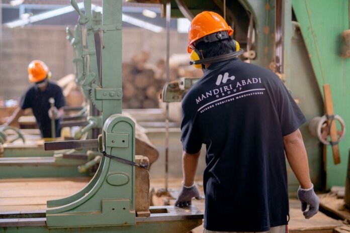 Workers wearing protective gear operating machinery in a factory environment, focusing on safety and production. Workers wearing protective gear operating machinery in a factory environment, focusing on safety and production.