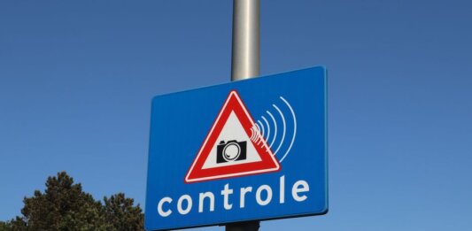 A blue road sign with a camera icon and 'controle' text indicates speed monitoring.