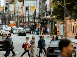A bustling urban crosswalk with pedestrians and traffic during the day.