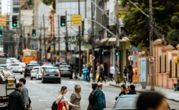 A bustling urban crosswalk with pedestrians and traffic during the day.