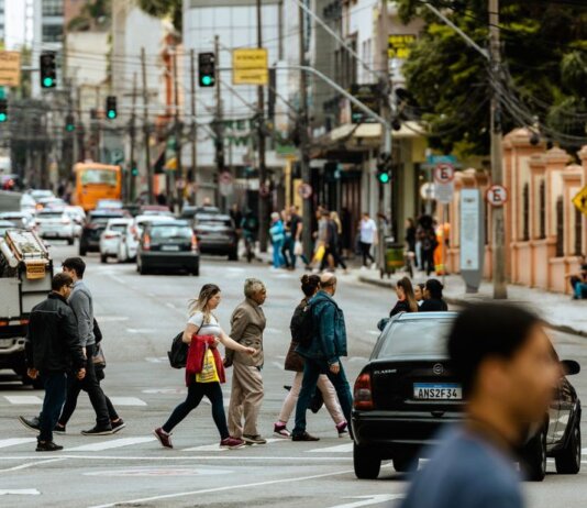 A bustling urban crosswalk with pedestrians and traffic during the day.