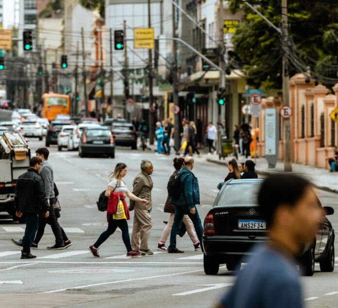 A bustling urban crosswalk with pedestrians and traffic during the day. A bustling urban crosswalk with pedestrians and traffic during the day.