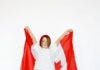 Канадское детское пособие увеличится в 2026–2027 годах A child joyfully holding a Canadian flag, celebrating patriotism and freedom.