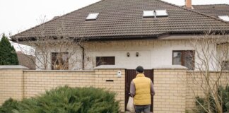 A delivery person brings a package to a suburban house on a winter day.