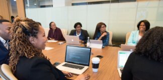 A diverse group of professionals working together in a modern conference room with laptops.