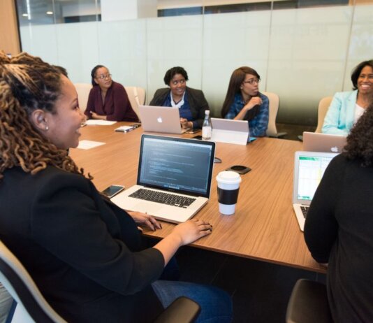 A diverse group of professionals working together in a modern conference room with laptops.