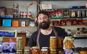 Министр Вальдес объявила о новых возможностях федеральных закупок для малого бизнеса A friendly shopkeeper stands behind shelves of homemade preserves.