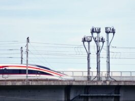 A high-speed train moves swiftly on an elevated railway under a clear sky.