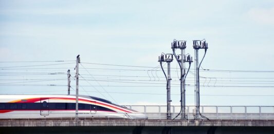 Оттава и Альберта будут сотрудничать в создании высокоскоростной железной дороги A high-speed train moves swiftly on an elevated railway under a clear sky.