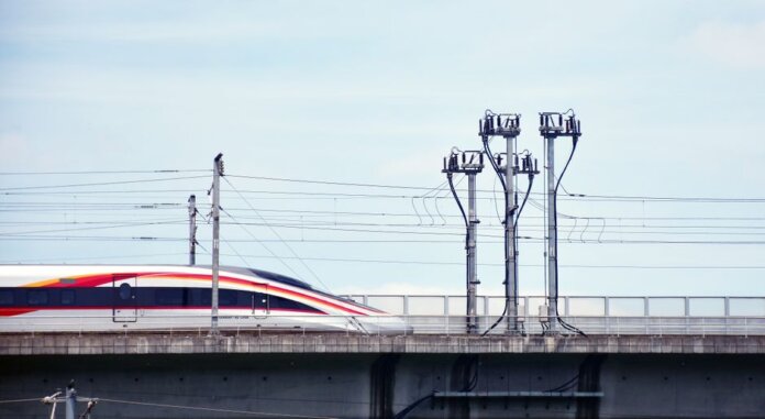 A high-speed train moves swiftly on an elevated railway under a clear sky. A high-speed train moves swiftly on an elevated railway under a clear sky.