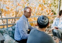A Jewish family enjoying a festive outdoor gathering during fall, sharing talks and wine.