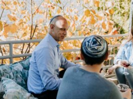 A Jewish family enjoying a festive outdoor gathering during fall, sharing talks and wine.