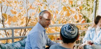 A Jewish family enjoying a festive outdoor gathering during fall, sharing talks and wine.