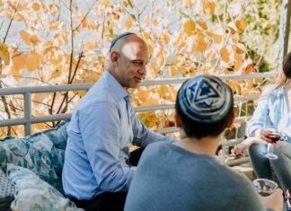 Пьер Пуальевр поздравил еврейские общины Канады с праздником Суккот A Jewish family enjoying a festive outdoor gathering during fall, sharing talks and wine.