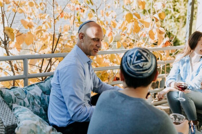 A Jewish family enjoying a festive outdoor gathering during fall, sharing talks and wine. A Jewish family enjoying a festive outdoor gathering during fall, sharing talks and wine.