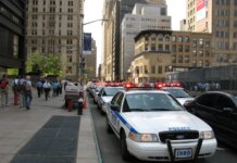 Пьер Пуалиевр едет в Нью-Йорк отстаивать безтарифную торговлю A line of NYPD police cars with flashing lights on a busy New York street, featuring pedestrians and tall buildings.