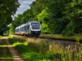 A modern passenger train moving through a scenic, green countryside, emphasizing travel and transportation.