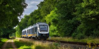 A modern passenger train moving through a scenic, green countryside, emphasizing travel and transportation.