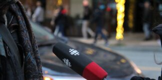 A person being interviewed on a Vancouver street, holding a microphone.